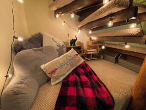 Un dormitorio acogedor con cama, estantería y luces colgantes.