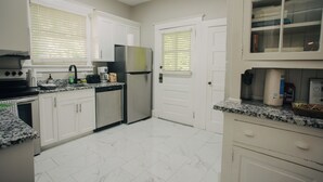 Una cocina con armarios blancos, un refrigerador de acero inoxidable, un microondas y una encimera de granito.