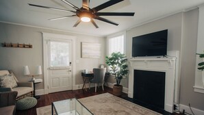 Una sala de estar con ventilador de techo, chimenea, televisor y comedor.