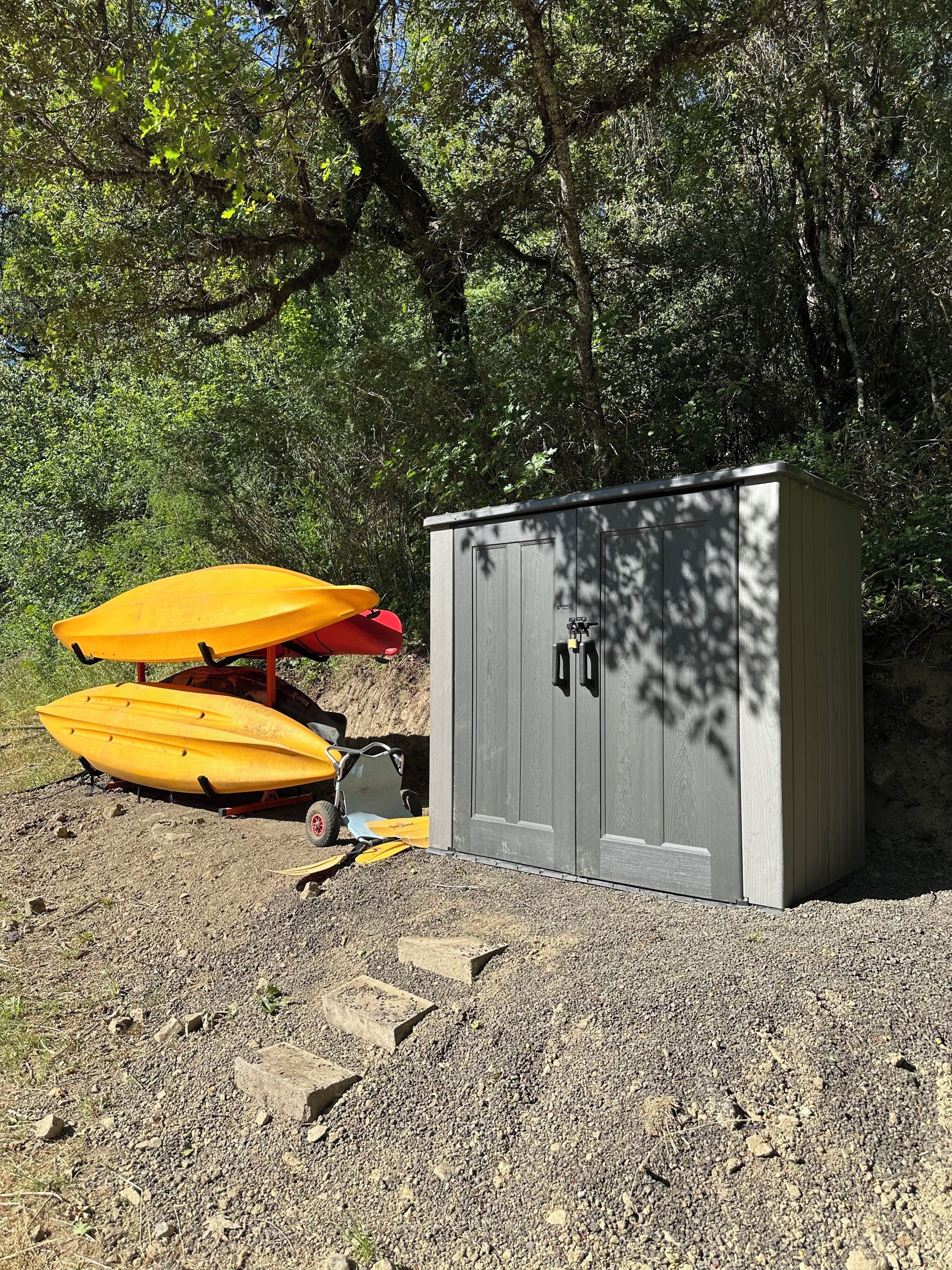 A gravel area with two yellow kayaks and a small shed.