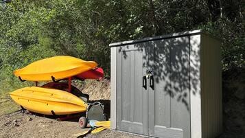 A gravel area with two yellow kayaks and a small shed.