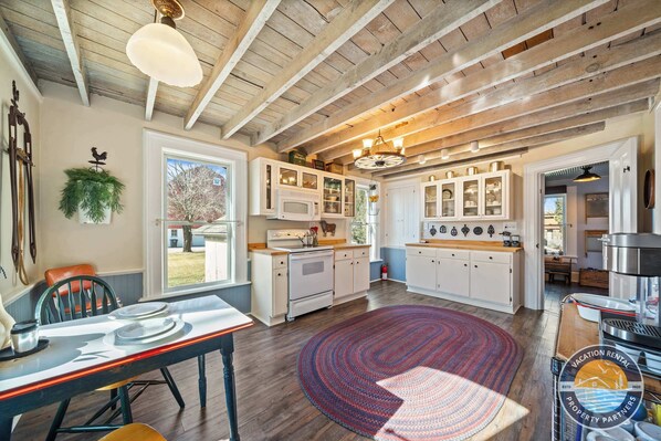 A spacious kitchen with wooden beams, white cabinetry, and a large island.
