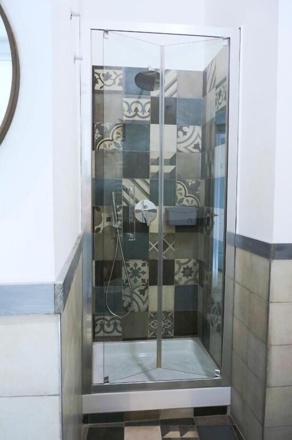 A glass-enclosed shower stall with patterned tiles.