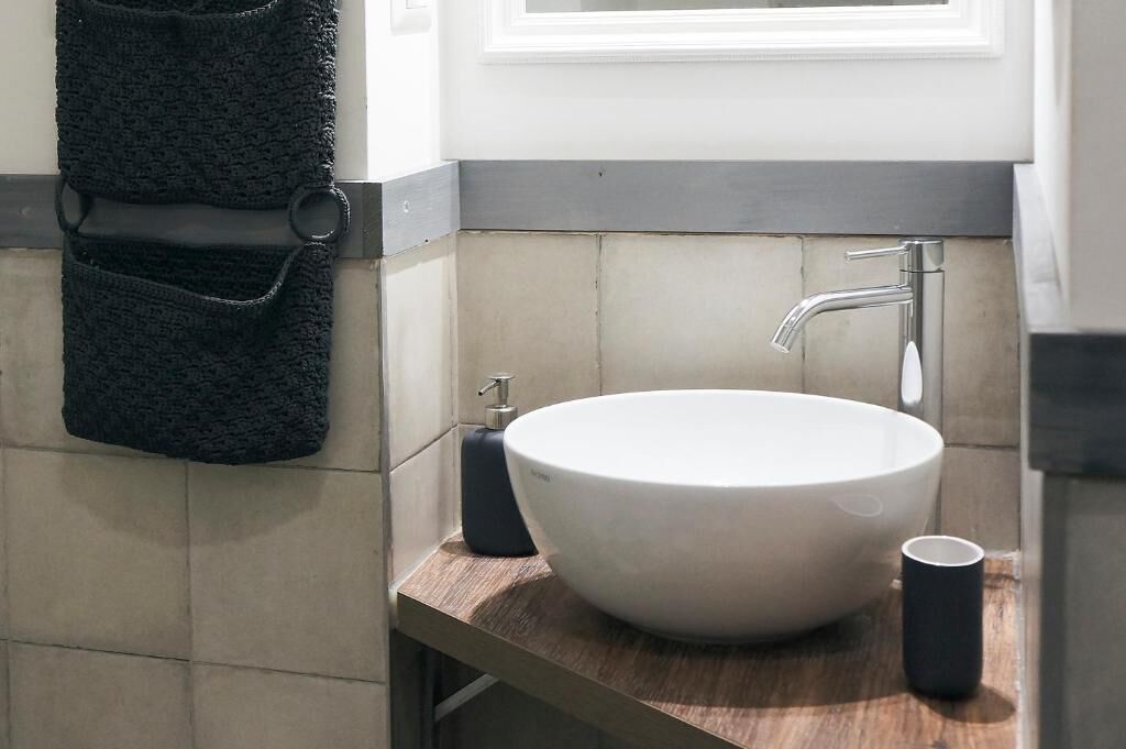 A bathroom with a white sink, a towel rack, and a cup on the counter.