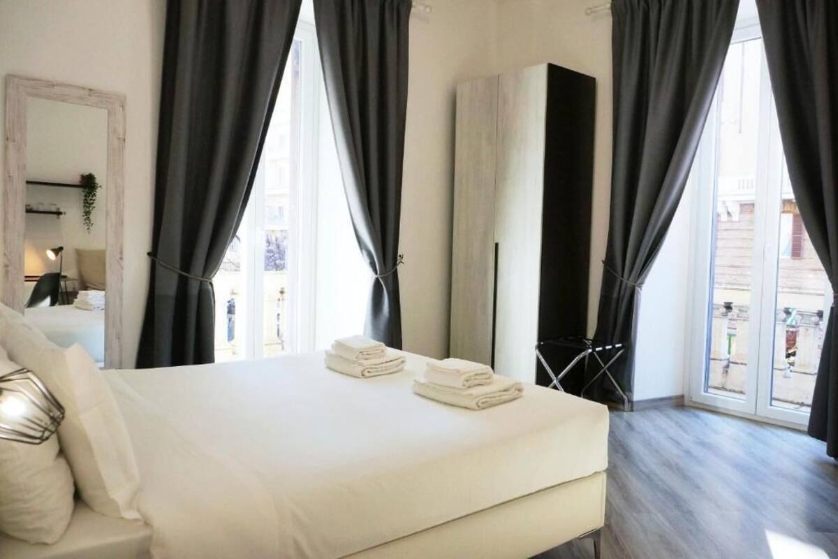 Ein Schlafzimmer mit einem Bett, einem Spiegel und einem Fenster mit Vorhängen.