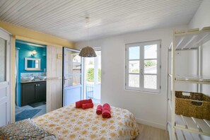 Un dormitorio con cama, ventana, balcón y kitchenette.