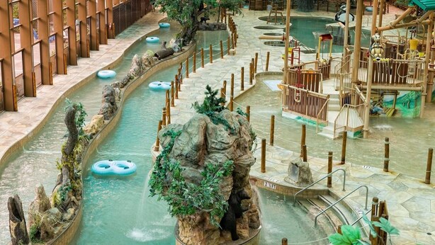 Ein großer Indoor-Wasserpark mit mehreren Wasserrutschen, aufblasbaren Ringen und einer Bären-Kletterlandschaft.