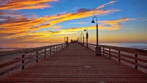 A wooden pier extending into the ocean with a sunset in the background.