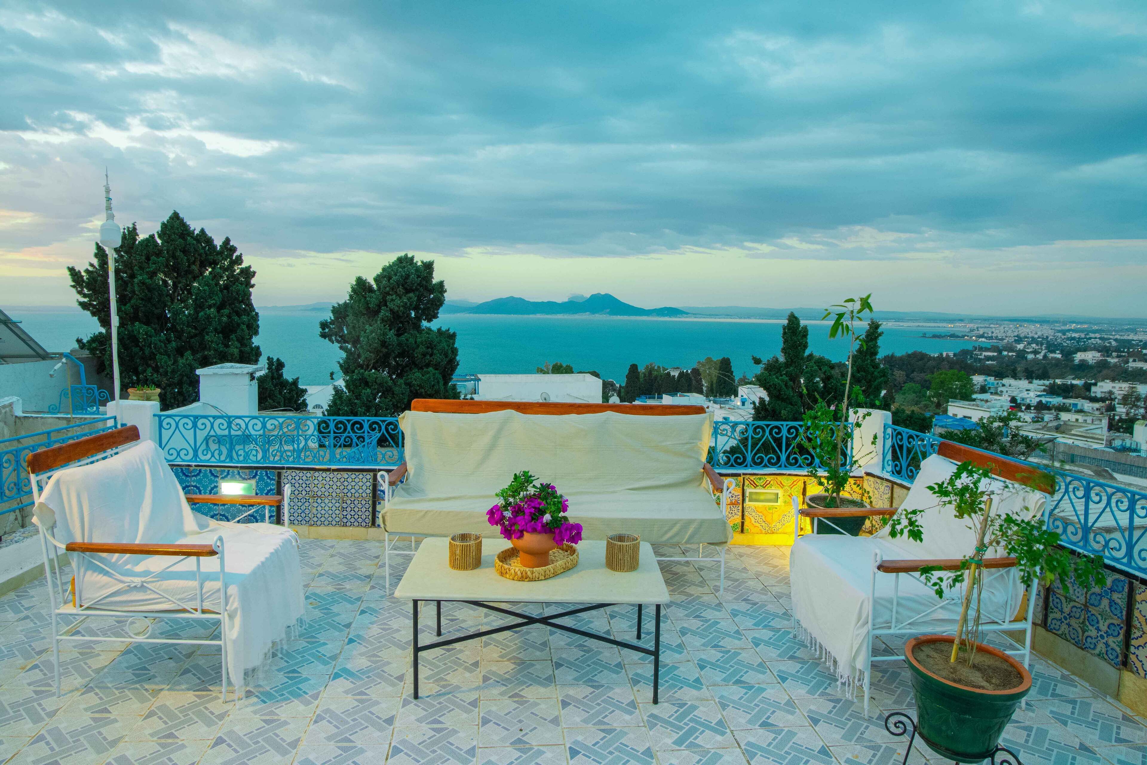 A terrace with a sofa, chairs, and a table with a flower vase.
