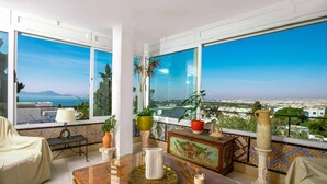 A balcony with a view of the city and sea, furnished with a table, chairs, and potted plants. - Maison l'Étoile de Sidi Bou Saïd  S 09 (Sidi Bou Said)