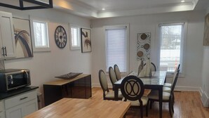 A modern kitchen with a wooden dining table, black bar stools, and a built-in microwave. - Cozy Compound Retreat Near Downtown & Highways (Detroit)