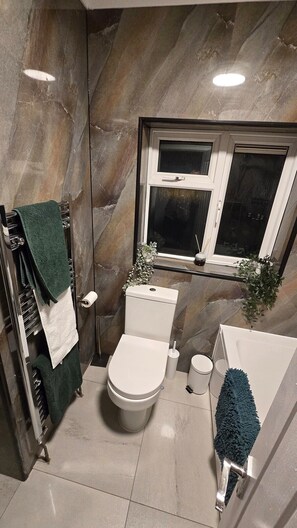 Pieni kylpyhuone, jossa on wc, bidee ja kylpyamme.