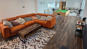 Una sala de estar moderna con un sofá modular, una mesa de billar y una alfombra estampada en patrón de espiga.