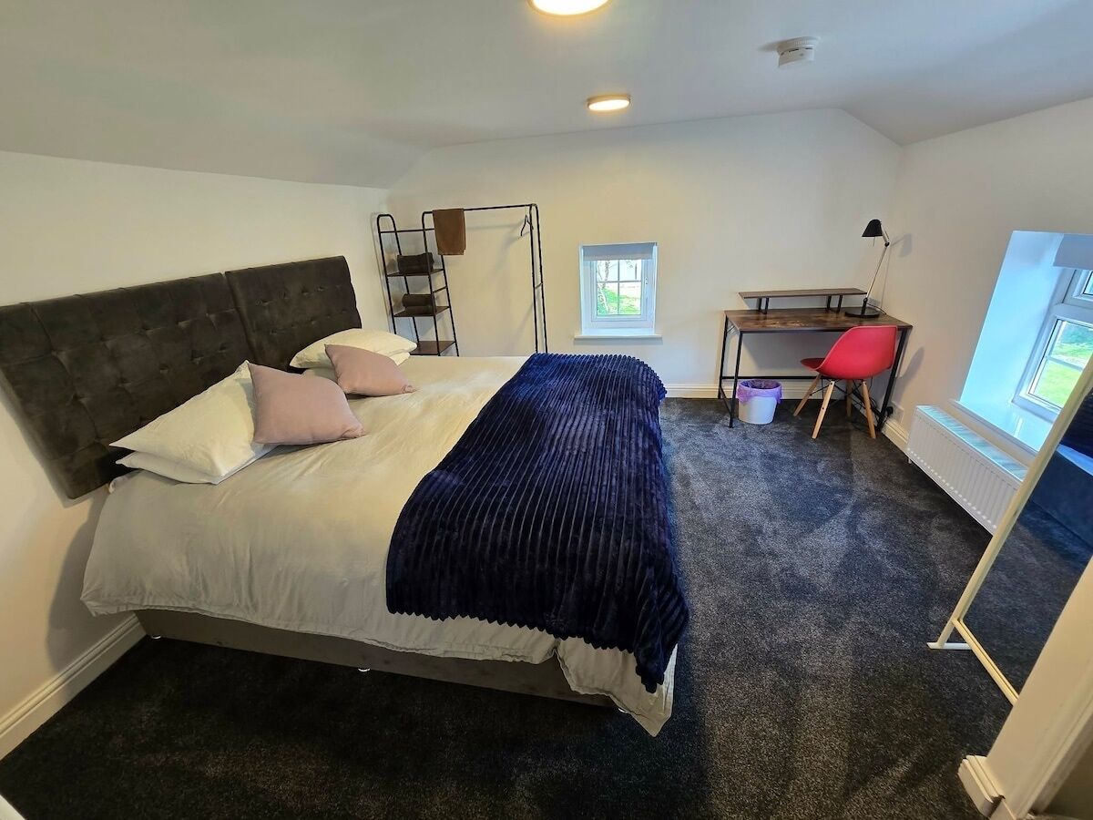 Une chambre à coucher comprenant un lit, un bureau, une chaise, une fenêtre et un radiateur.