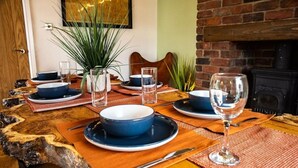 Una mesa de comedor dispuesta con fuentes azules, platos y una copa de vino, rodeada de individuales tejidos y una mesa de madera rústica.