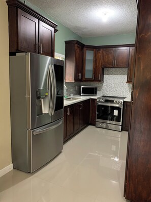 A kitchen with a stainless steel refrigerator, microwave, oven, and wooden cabinets.