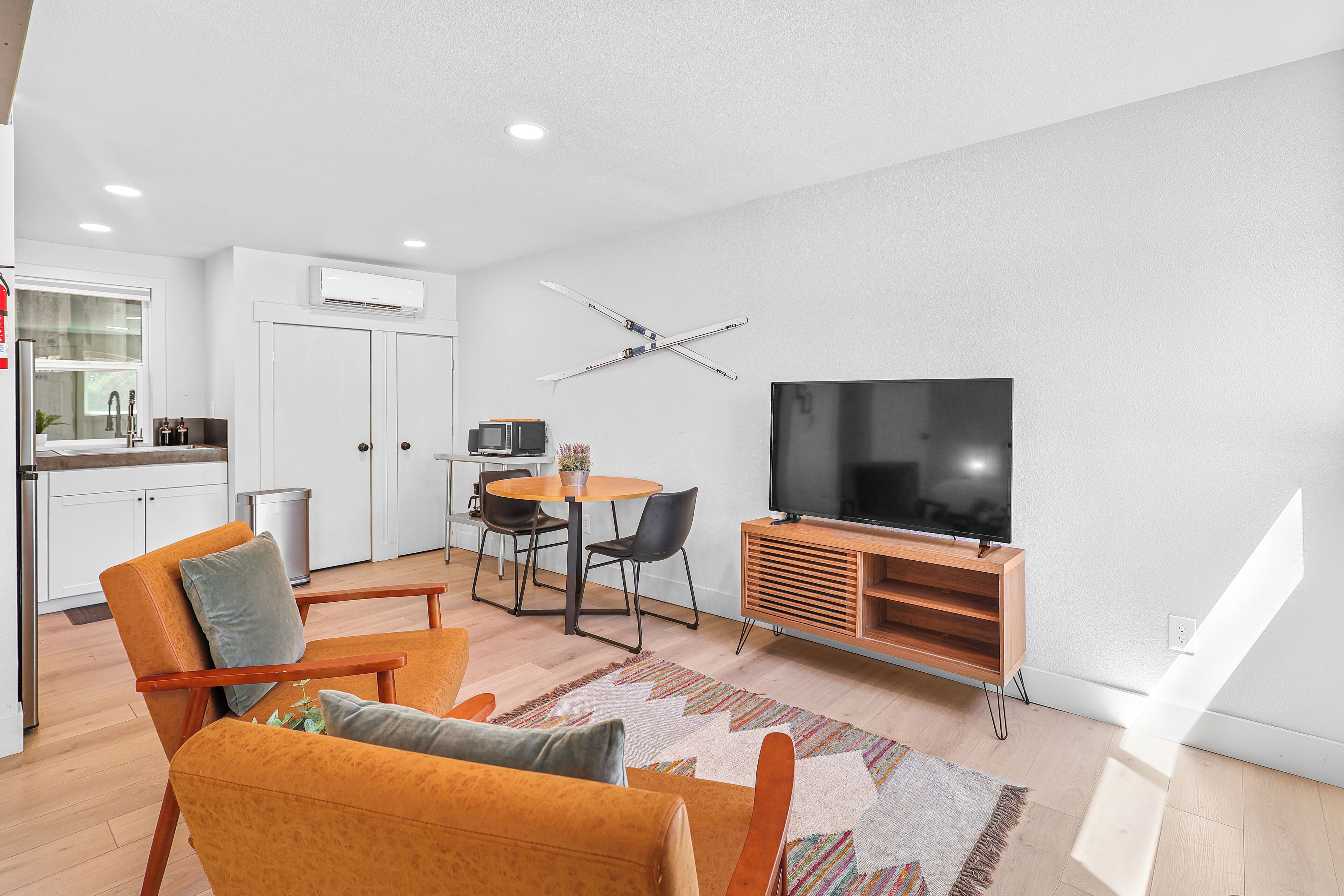 A modern living room with a sofa, TV, and dining area.