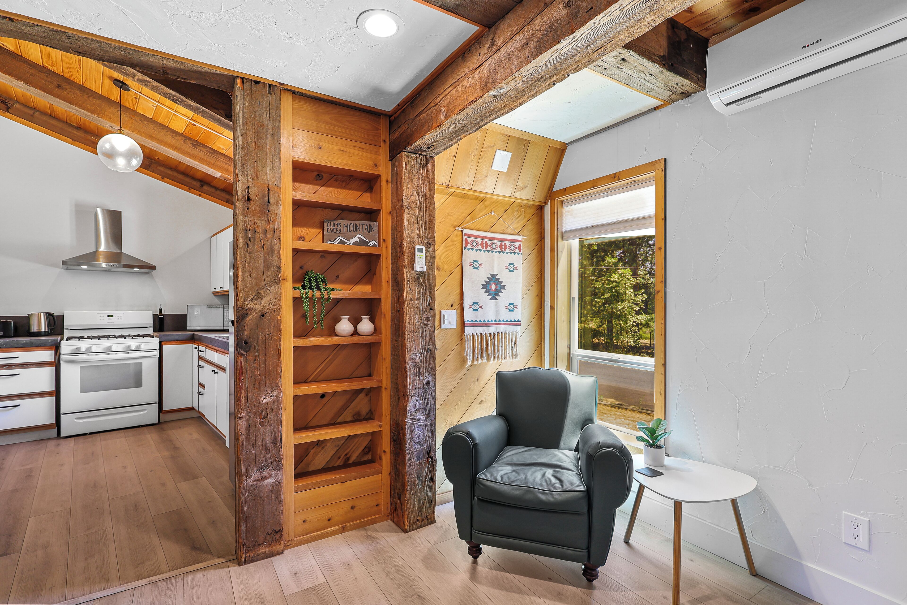 A kitchen with white appliances, a wooden shelf unit, and a black leather chair.