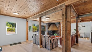 A spacious room with a high ceiling, wooden beams, and a stone fireplace. - Basecamp Lodge (Mount Shasta)
