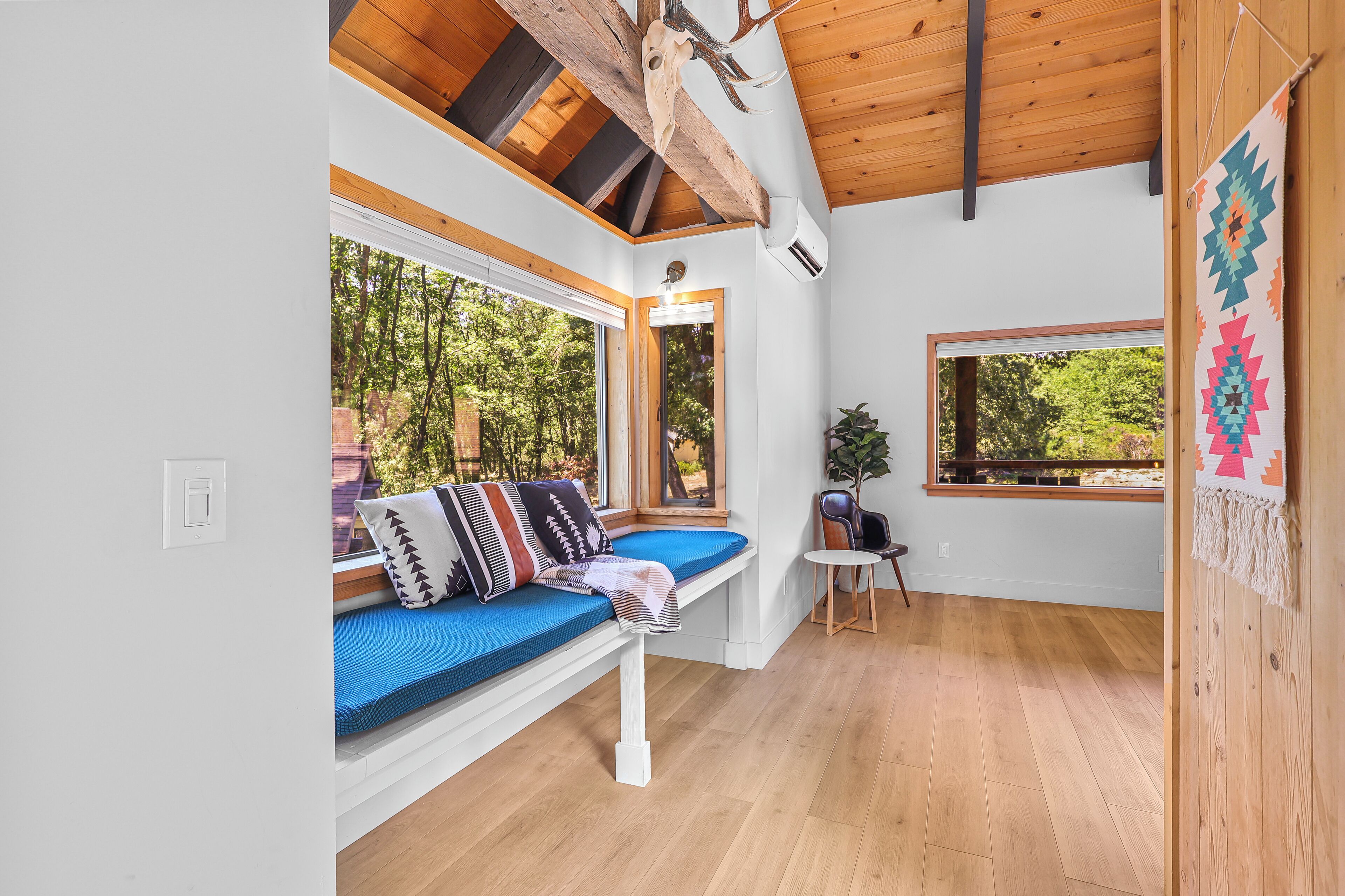 Una habitación acogedora con un banco incorporado, ventanas amplias y techo de madera.