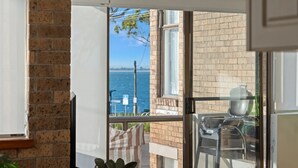 A balcony with a view of the sea, a brick wall, and a glass door. - Shoal Bay Beachfront Escape (Shoal Bay)