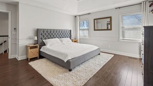 A bedroom with a large bed, a ceiling fan, a nightstand, a dresser, and a window with blinds. - A Home away from home - family friendly, central (Kansas City)