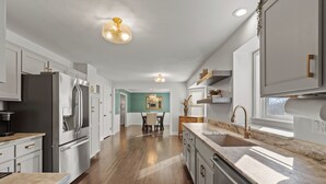 A modern kitchen with stainless steel appliances, a marble countertop, and a view into the dining area. - A Home away from home - family friendly, central (Kansas City)