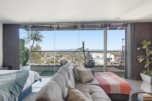 A modern living room with a large window, a sofa, a coffee table, and a hanging chair.