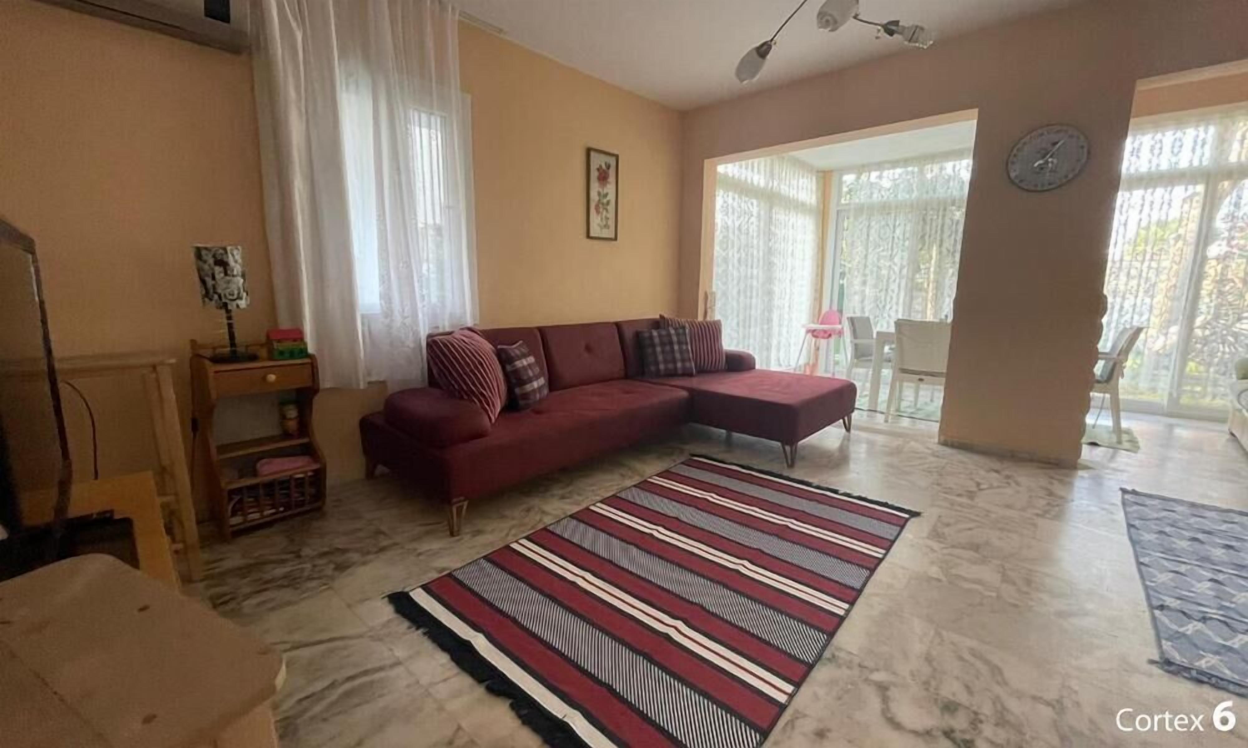 Una sala de estar con sofá, alfombra a rayas y una ventana con cortinas.