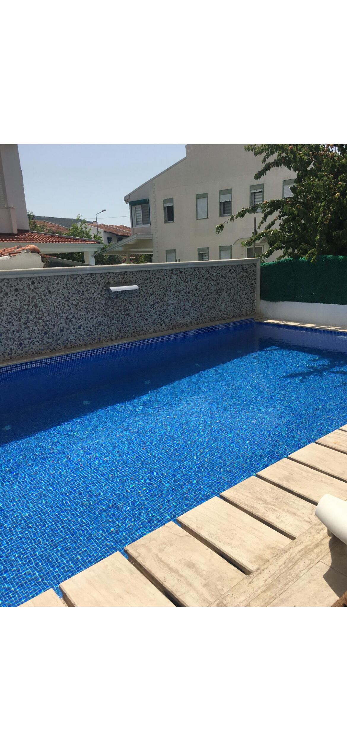 A swimming pool with a tiled edge and a stone wall.