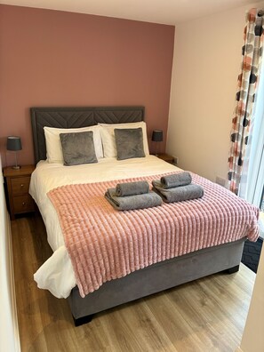 A bed with a headboard, pillows, a blanket, and two bedside lamps. - Pet Friendly Cottage with Sea Views (Saundersfoot)