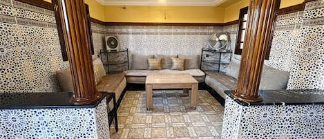 A room with a patterned floor, a sofa, a coffee table, and decorative items on side tables.