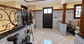 Ένα δωμάτιο με ένα δάπεδο με σχέδια, μια μαύρη πόρτα και ένα παγκάκι.