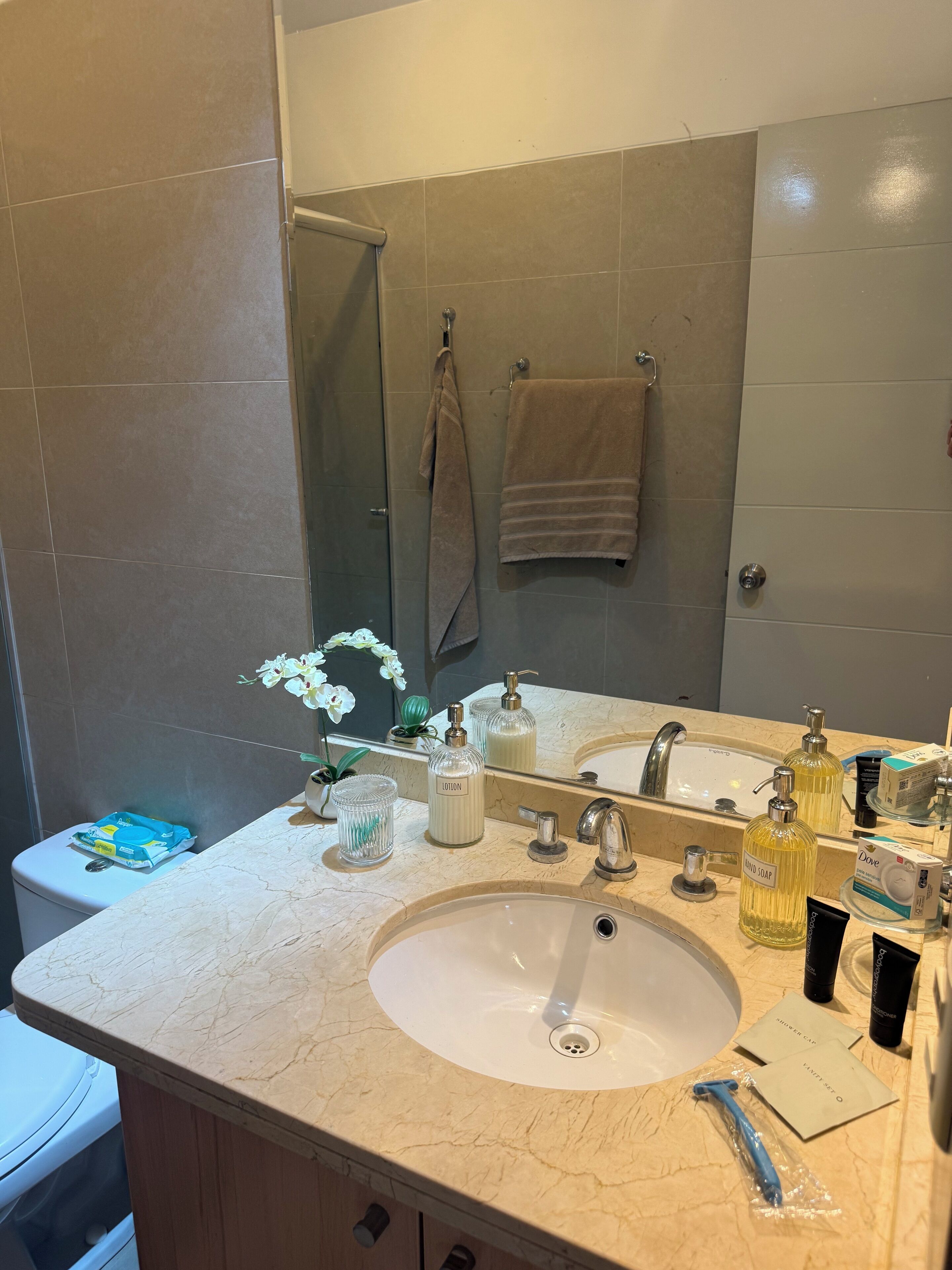 Ein Badezimmer mit einem weißen Waschbecken, zwei Spiegeln, einem Handtuchhalter und Toilettenartikeln.
