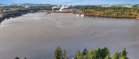 Une vaste étendue d’eau, avec des installations industrielles et de la fumée visible au loin.