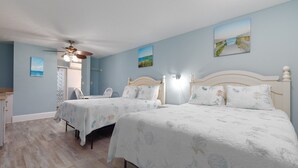 Ein Schlafzimmer mit zwei Betten, einem Deckenventilator und Kunstwerken an den Wänden.
