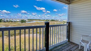 A covered porch with a view of a grassy area and distant buildings. - Surf City Getaway– Cozy Suite - Walk to Beach (Surf City)