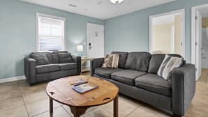 A living room with two grey sofas, a wooden coffee table, and a ceiling fan. - Surf City Getaway– Cozy Suite - Walk to Beach (Surf City)