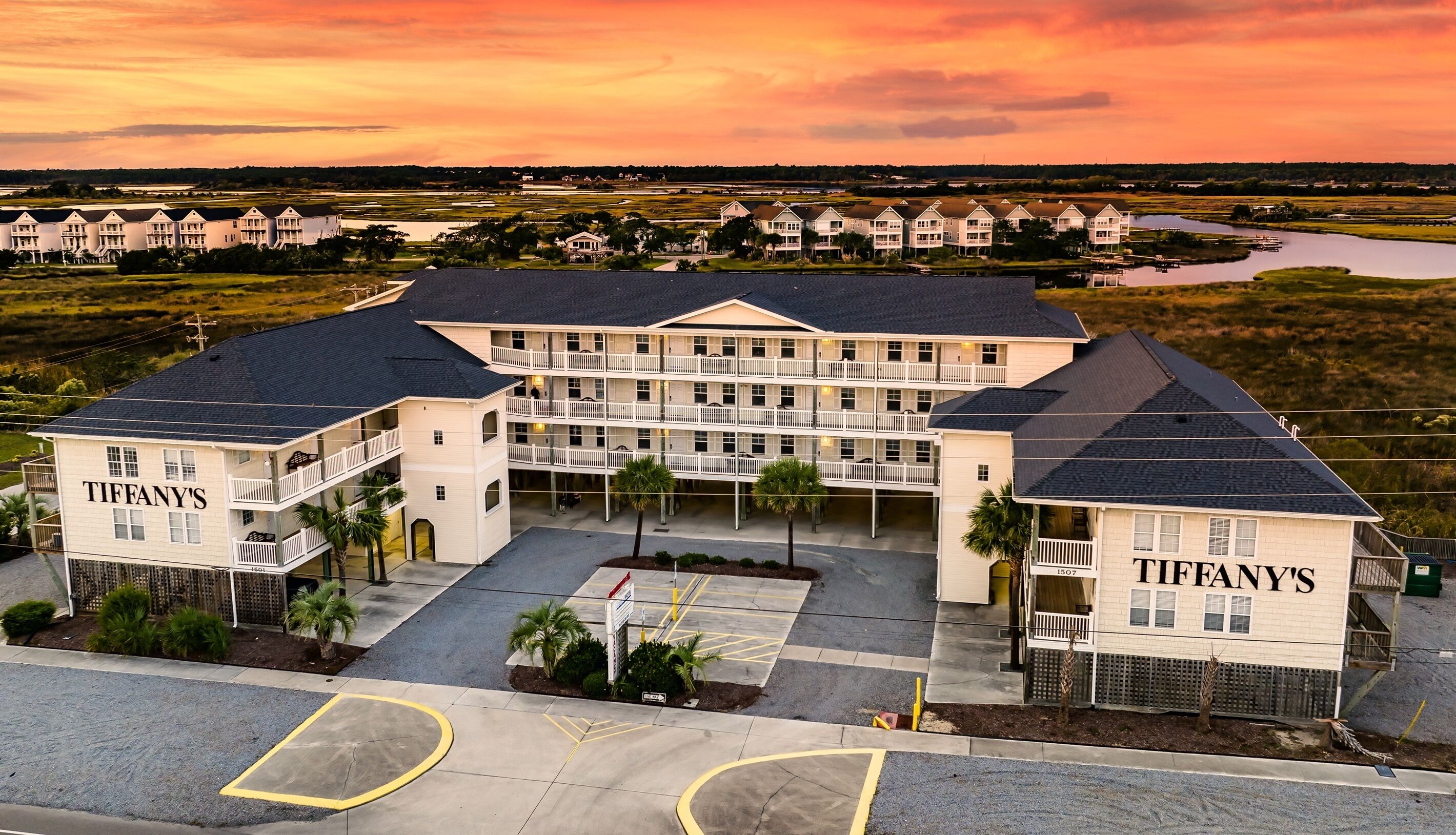 A multi-story hotel with a central courtyard, named 'TIFFANY'S', featuring balconies and a view of a lake.