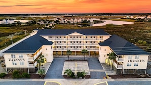 Un gran hotel de varios pisos con fachada simétrica, un patio central y vistas a un río y al paisaje circundante al atardecer.
