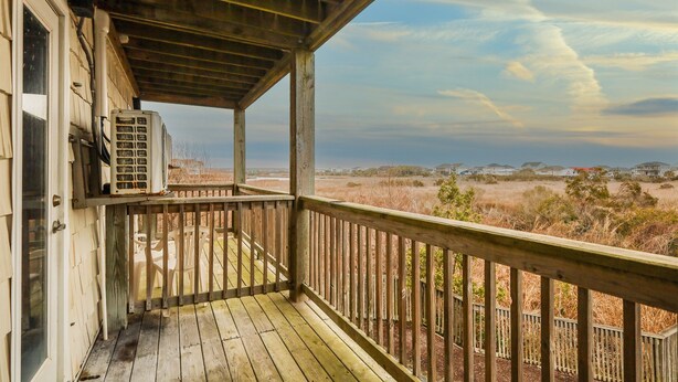 A wooden deck with a view of a grassy field and distant buildings. - Surf City Getaway - Motel Unit - Walk to Beach (Surf City)