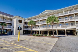 A multi-story hotel with balconies, parking area, and palm trees. - Surf City Getaway - Motel Unit - Walk to Beach (Surf City)