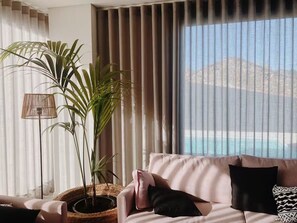 Una sala de estar con un sofá, una planta en maceta y vistas a una masa de agua a través de amplios ventanales.
