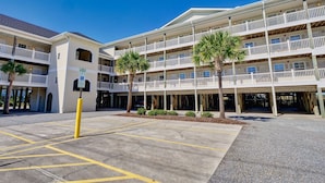 A multi-story hotel with balconies, parking area, and palm trees. - Surf City Stay - Motel Unit - Walk to Beach (Surf City)