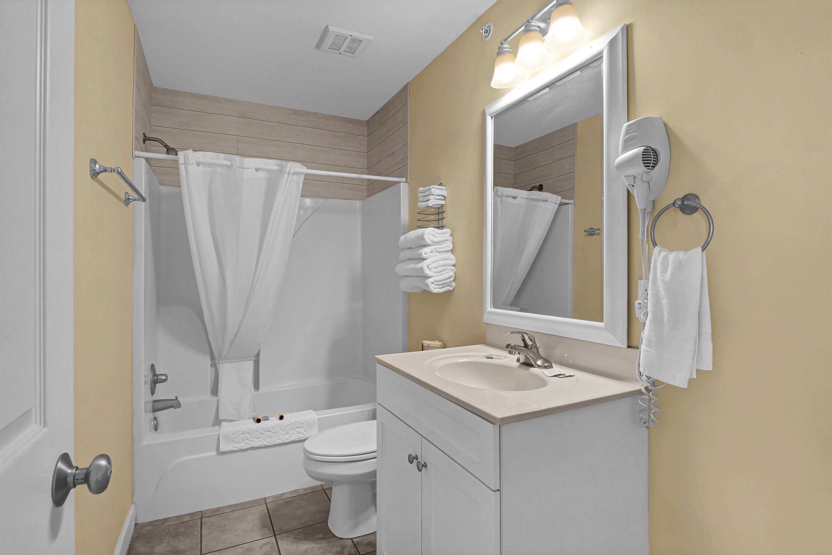 A bathroom with a bathtub, toilet, sink, and a mirror.