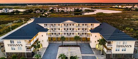 A large, multi-story hotel with a symmetrical facade, a central courtyard, and a view of a river and surrounding landscape at sunset.