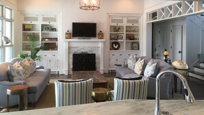 Un salon moderne avec une cheminée, un canapé, des fauteuils et un téléviseur.