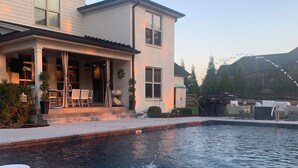 Une piscine résidentielle avec un espace patio, un coin salon couvert et une vue sur une montagne en arrière-plan.