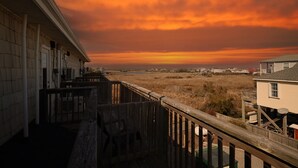 A wooden deck overlooking a grassy area with a view of the horizon and distant buildings. - Surf City Getaway - Walk to Beach - Seasonal Pool (Surf City)