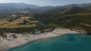 Vista aérea de un paisaje costero con un río, campos y montañas.